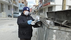 Yerlere atılan maskeleri topluyor