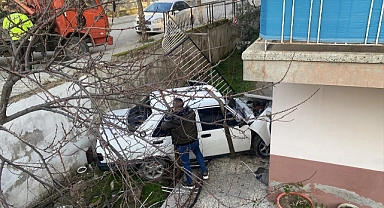İzmir'de yoldan çıkan otomobil bir apartmanın bahçesine düştü